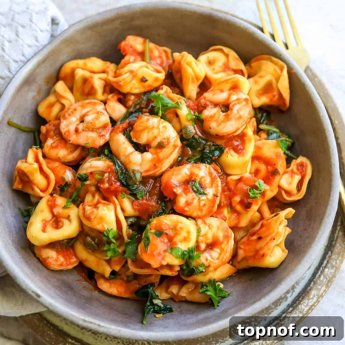 Fra Diavolo Shrimp Tortellini 6 A close-up photo of perfectly cooked shrimp in a white bowl, with a fork on the side, highlighting its juicy texture.