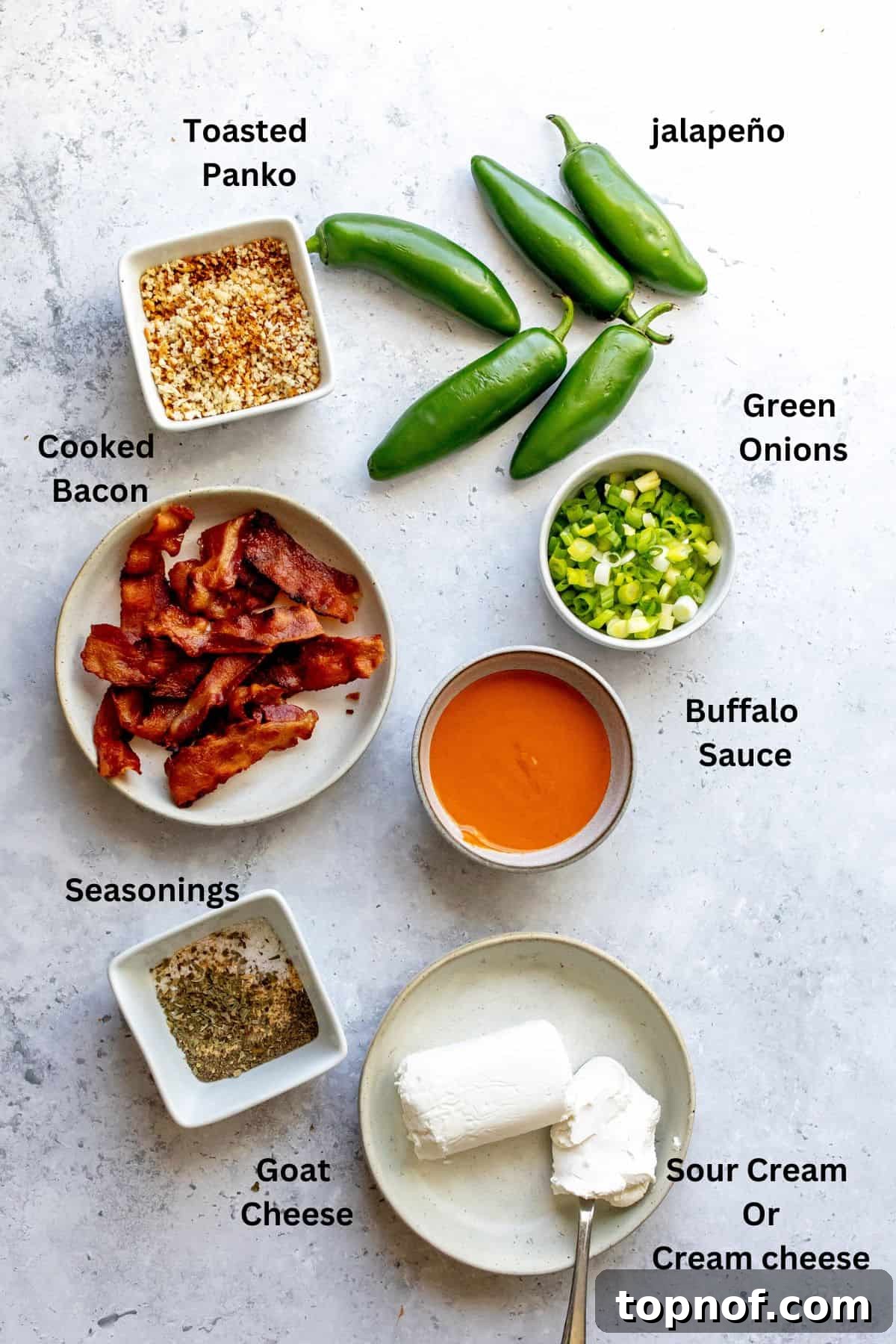 All the essential ingredients for making oven baked jalapeño poppers, including fresh jalapeños, cheese, sour cream, and spices, beautifully arranged in small preparation bowls on a clean kitchen counter.