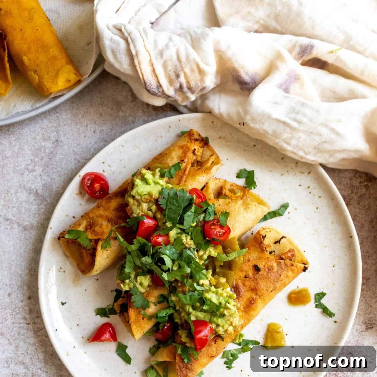 Golden Crisp Chicken Taquitos 6 Delicious baked chicken taquitos on a white plate, generously topped with fresh salsa, cilantro, and creamy avocado slices, ready to be enjoyed.