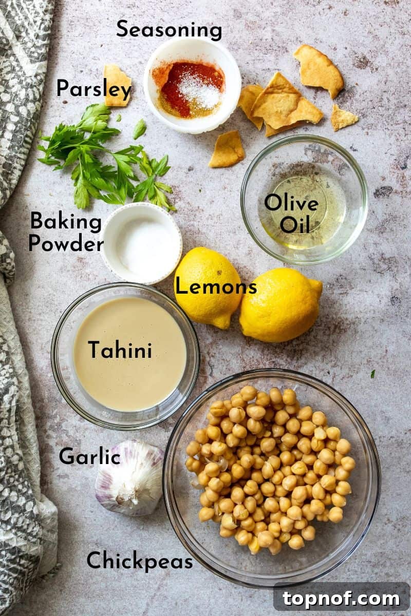 Velvety Smooth Hummus Recipe 3 Creamy Hummus Recipe ingredients on a counter in bowls, showing fresh lemon, garlic, tahini, and spices.