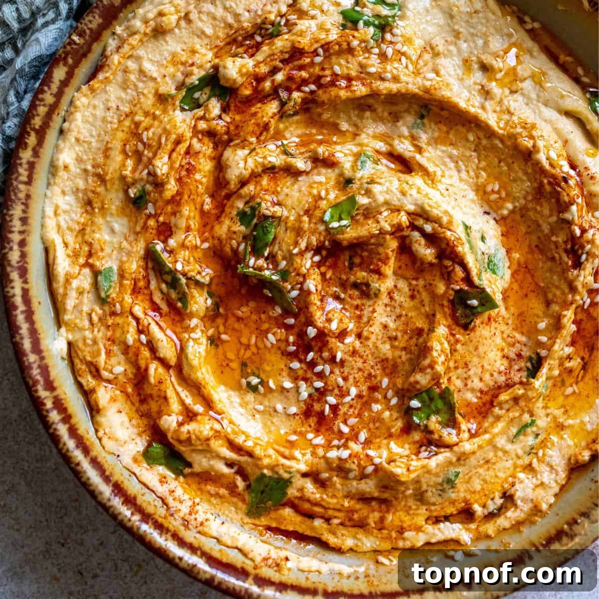Velvety Smooth Hummus Recipe 5 Creamy Hummus Recipe up close in a bowl with sesame seeds, showcasing the smooth texture and appealing garnish.