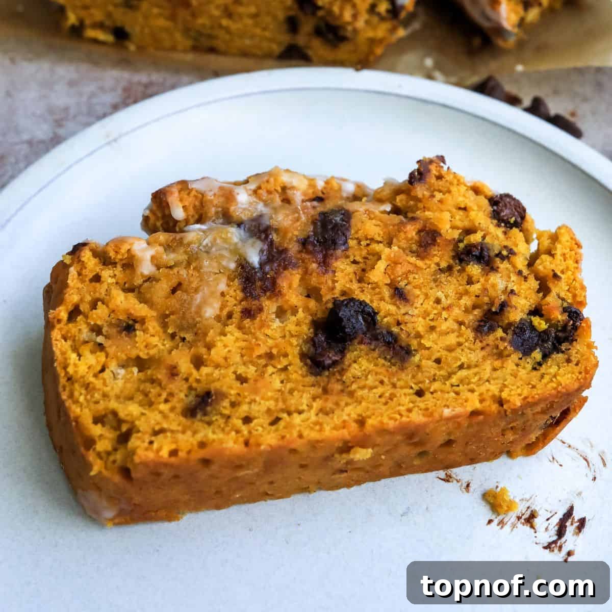 Decadent Chocolate Pumpkin Loaf 5 Easy Pumpkin Bread on a white plate, drizzled with icing and ready to eat.