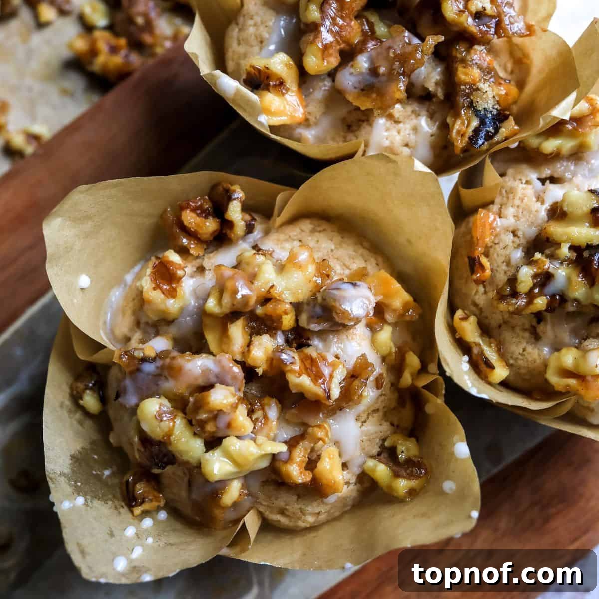 Bakery Style Cinnamon Muffins with Candied Walnuts 6 A close-up shot of a single cinnamon muffin, showcasing its perfectly baked texture and generous topping of candied walnuts, ready to be enjoyed.