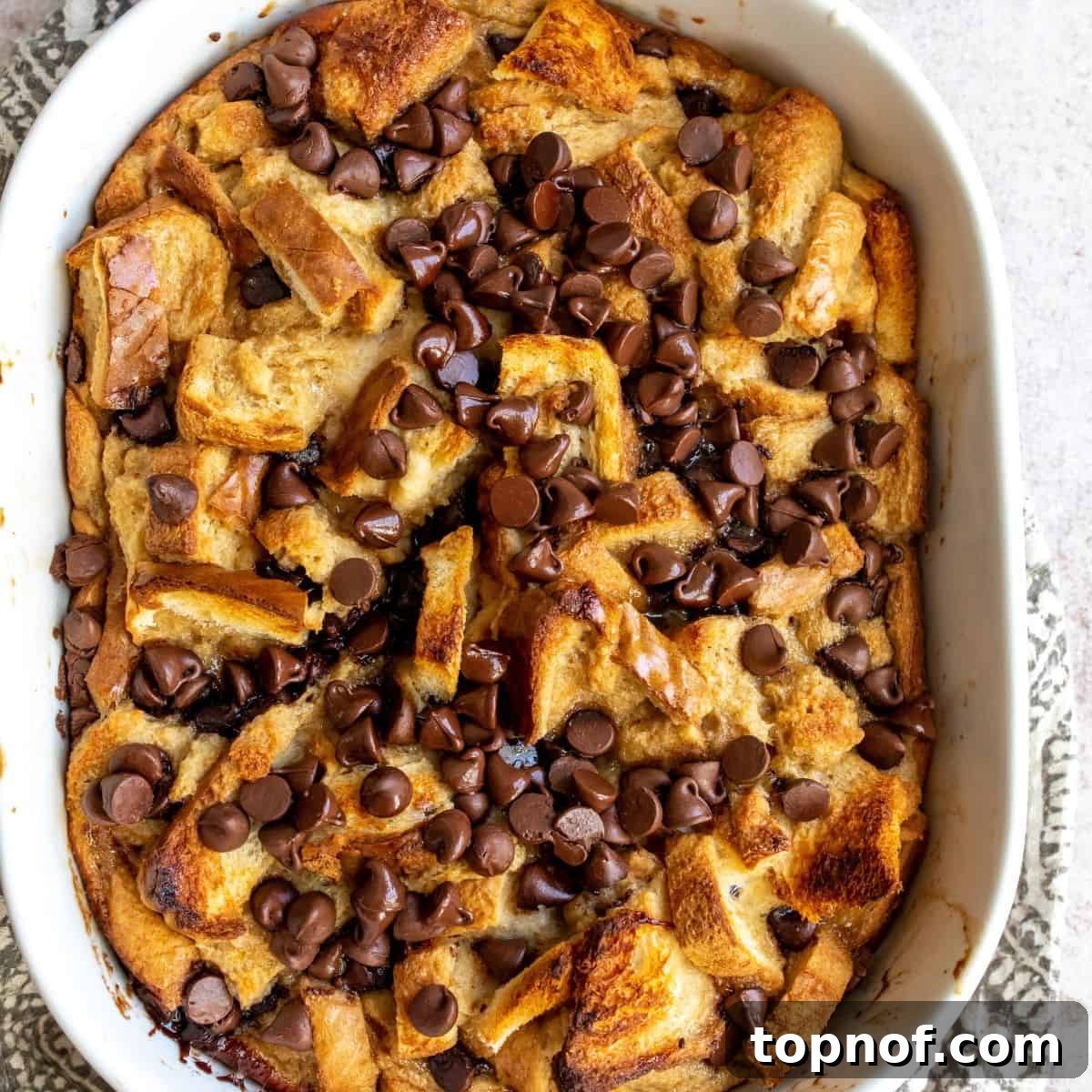 Irresistible Chocolate Chip Bread Pudding 2 Chocolate Chip Bread Pudding up close in a casserole dish, ready to be served, showing its crispy top and soft interior.