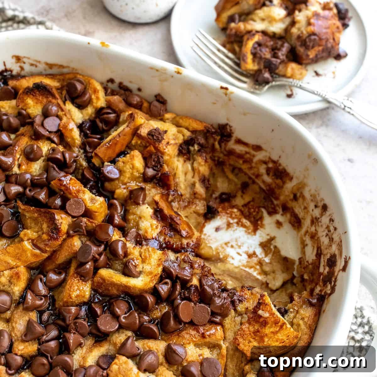 Irresistible Chocolate Chip Bread Pudding 6 A close-up shot of the perfectly baked Chocolate Chip Bread Pudding, golden brown and inviting, in a white casserole dish.