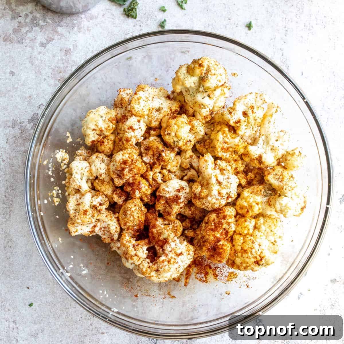 Seasoned Cauliflower for Roasting Cauliflower florets seasoned with herbs and olive oil in a bowl, prepared for roasting.