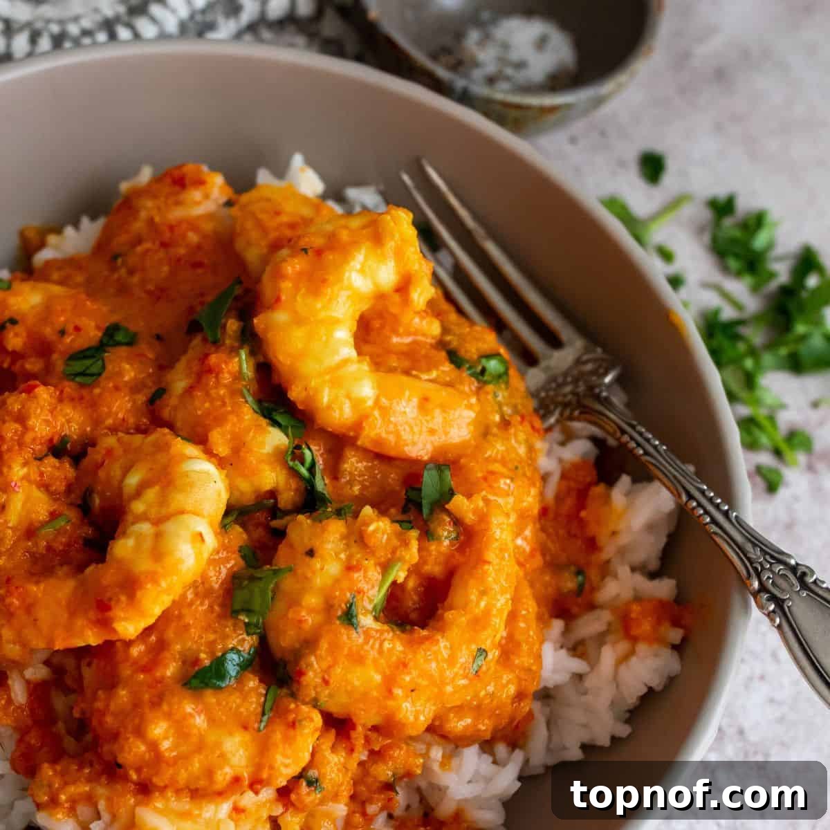 Velvety Coconut Shrimp Curry 2 A vibrant and appetizing Coconut Shrimp Curry served in a stylish grey bowl, generously garnished with fresh cilantro.