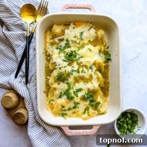 Green Chili Chicken Enchiladas in a light pink casserole dish with cilantro on the side.