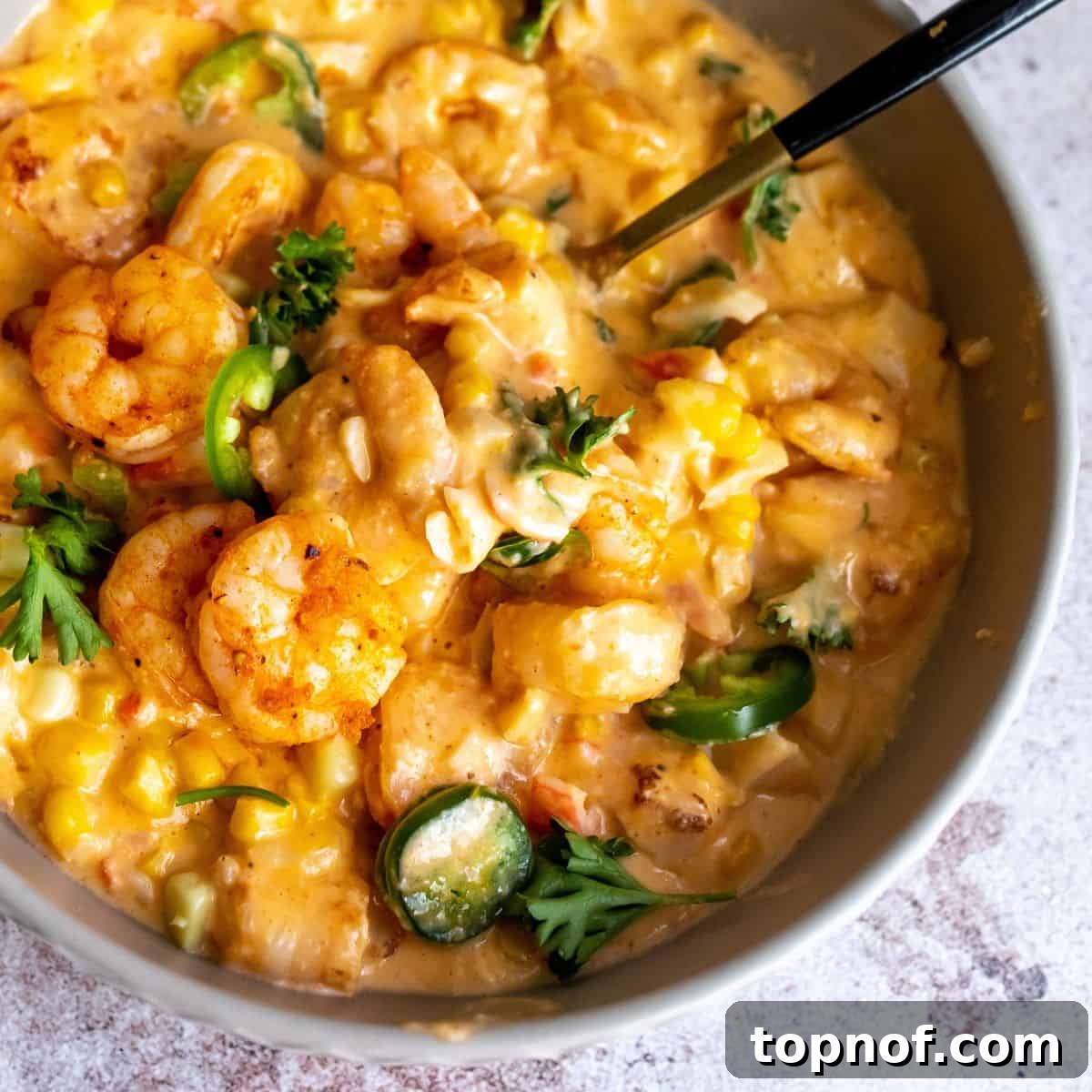Velvet Shrimp and Sweet Corn Bisque 6 Close-up shot of the shrimp and corn bisque in a bowl with a black spoon, highlighting its creamy texture.