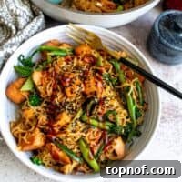 Teriyaki Salmon Noodles in a white bowl with a black fork.