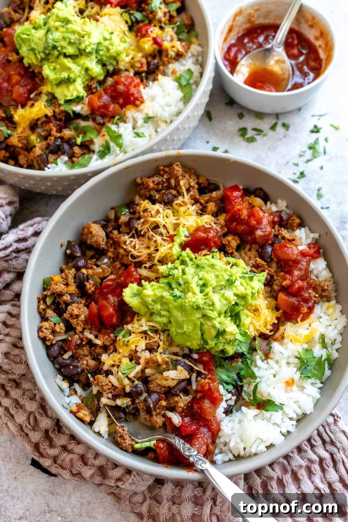 Loaded Taco Rice Bowl 2 A vibrant Taco Rice Bowl with seasoned meat, rice, fresh cilantro, and guacamole on top.