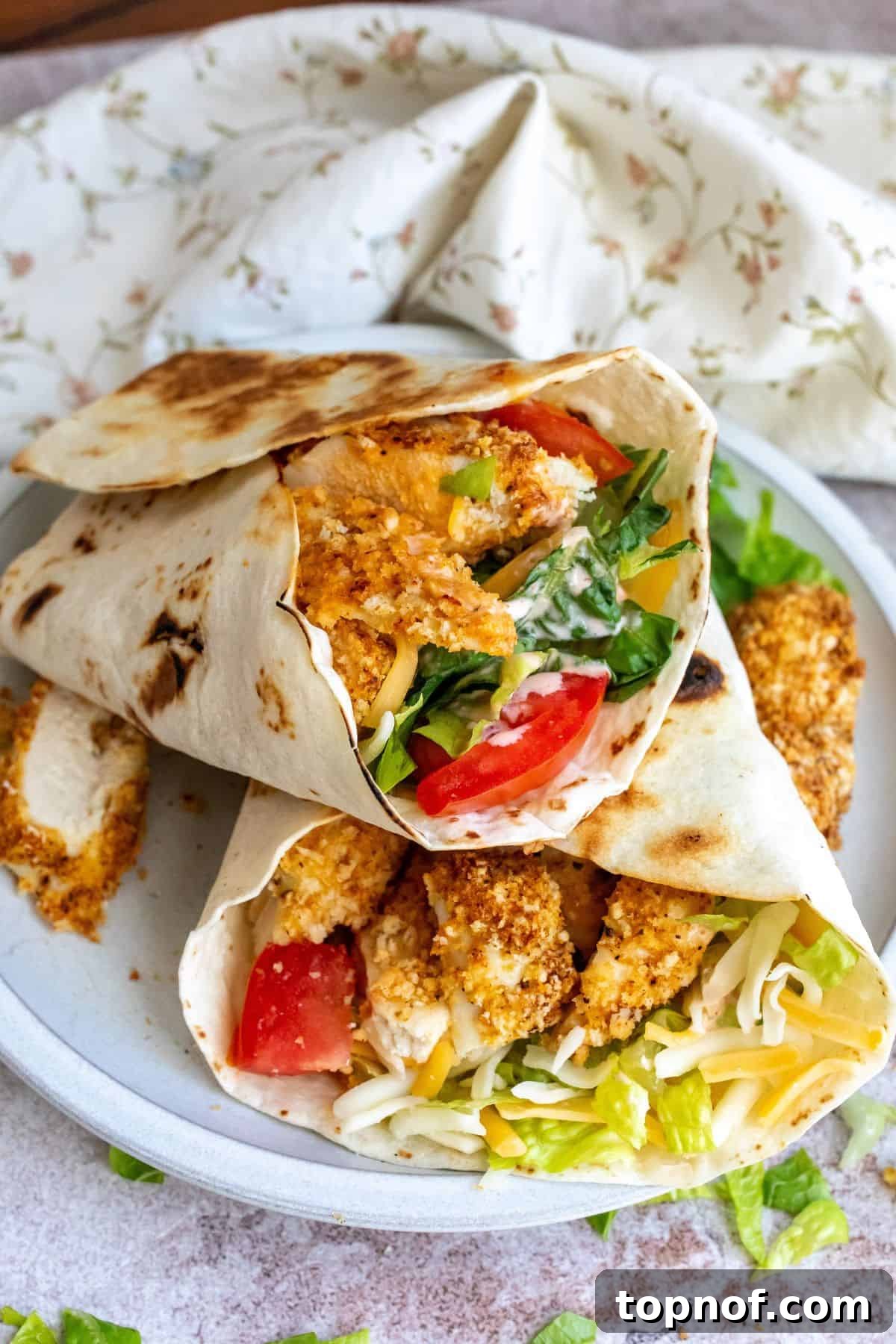 Crispy Chicken Delight 2 Crispy chicken in a wrap with fresh lettuce and ripe tomato, beautifully arranged on a plate. The wrap is golden and inviting, ready to be enjoyed.