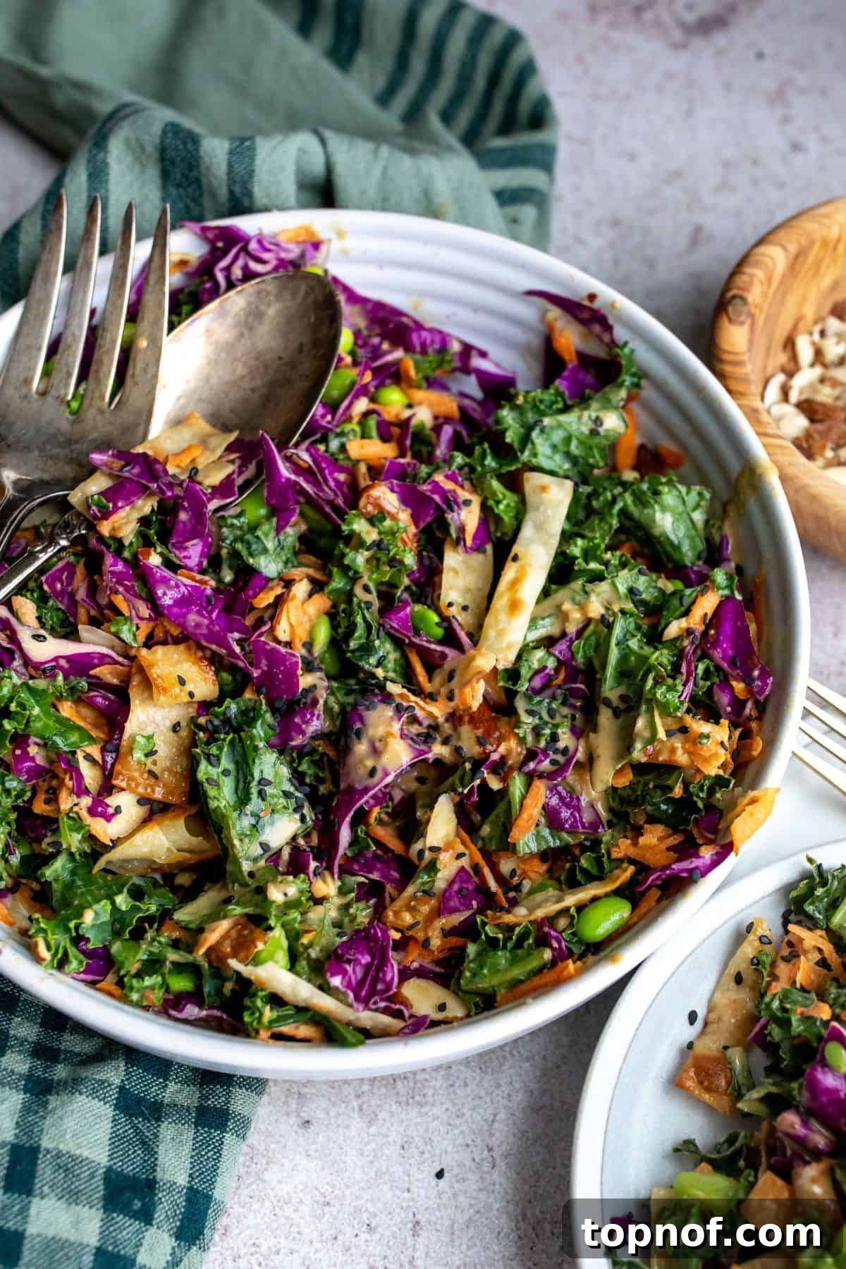 Crunchy Asian Cabbage Slaw 2 Asian Cabbage Salad in a large serving bowl with serving utensils. A visually appealing salad with vibrant colors, ready to be served.