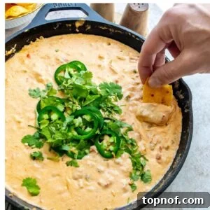 Smoked Queso in a black cast iron with jalapeños on top.