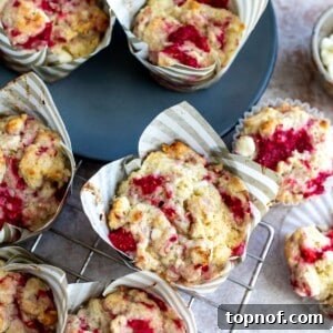 Freshly baked Raspberry White Chocolate Muffins on a cooling rack with a grey plate nearby.
