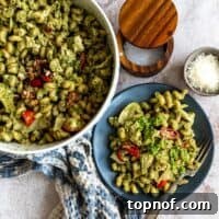 A mouthwatering close-up of Tuna Pesto Pasta, showcasing the vibrant green pesto coating the pasta, mixed with flaky tuna and colorful vegetables, ready to be devoured.
