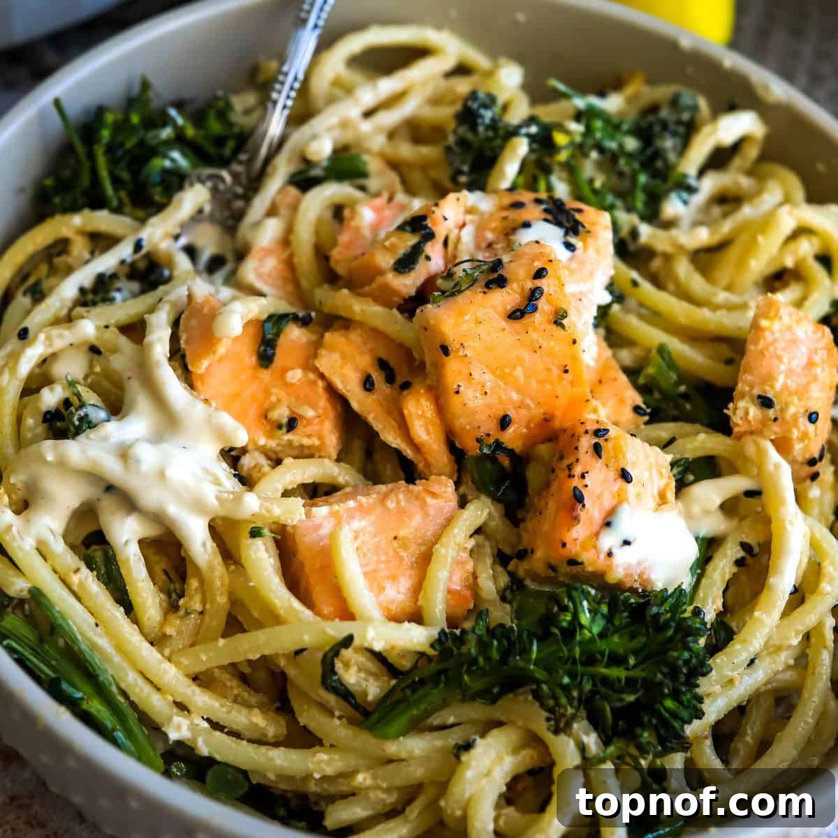 Mediterranean Salmon Tahini Pasta 6 A close-up view of creamy tahini pasta topped with succulent miso garlic butter salmon bites and vibrant roasted broccolini, garnished with sesame seeds, ready to be enjoyed.