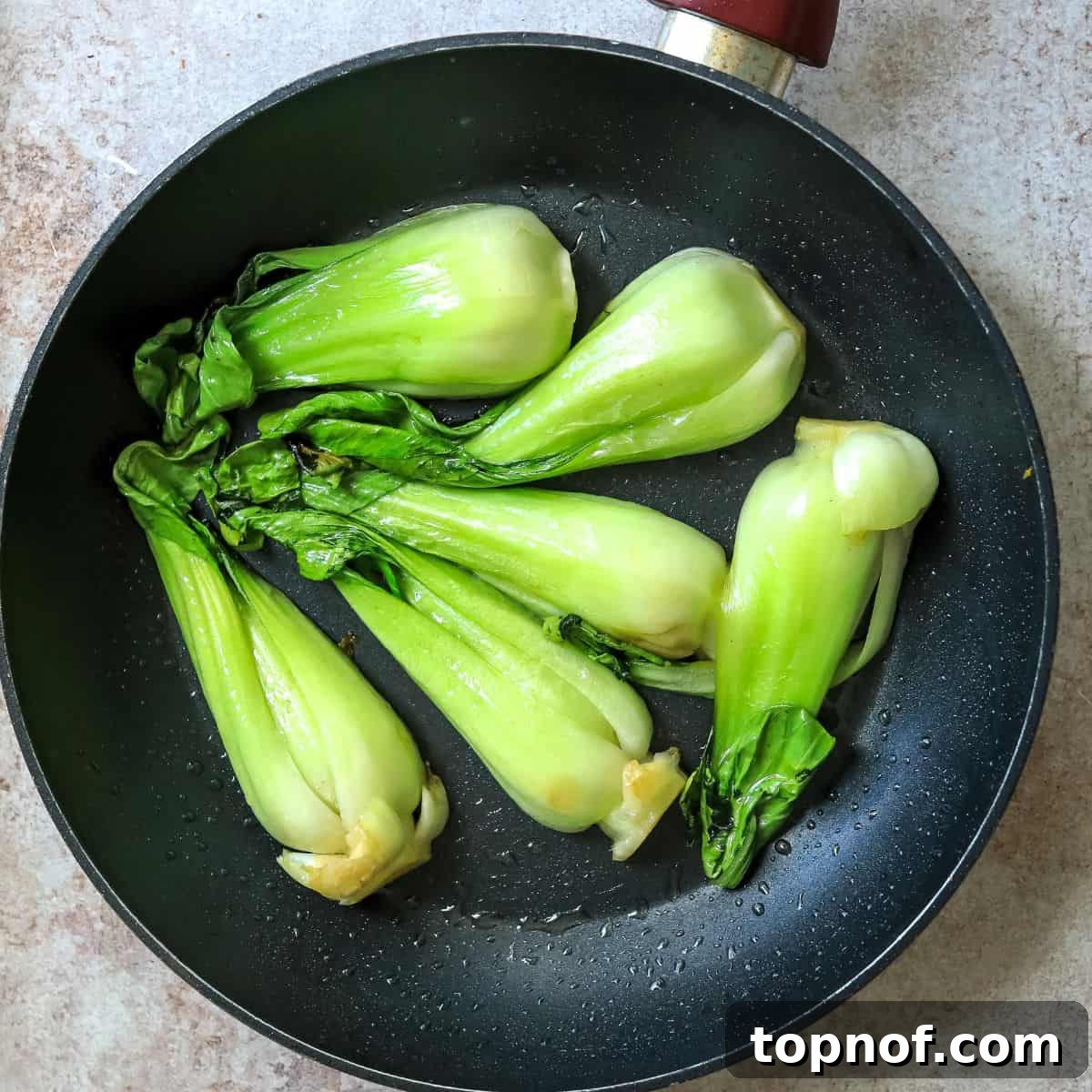 Savory Furikake Crusted Salmon 6 Black fry pan with vibrant green sautéed baby bok choy, showcasing its char and tenderness.