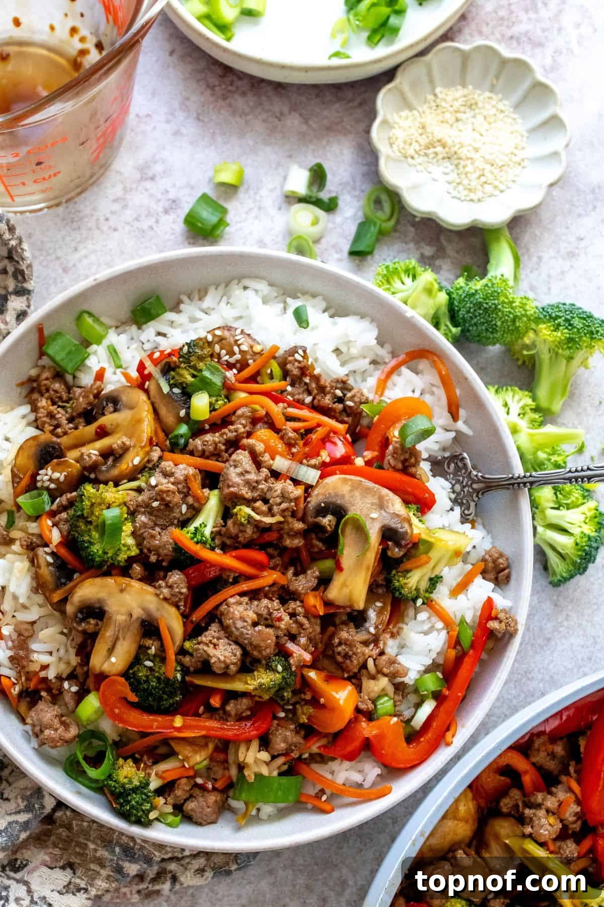 Savory Ground Beef Stir Fry 2 White bowl with ground beef Teriyaki over rice, garnished with sesame seeds and green onions.