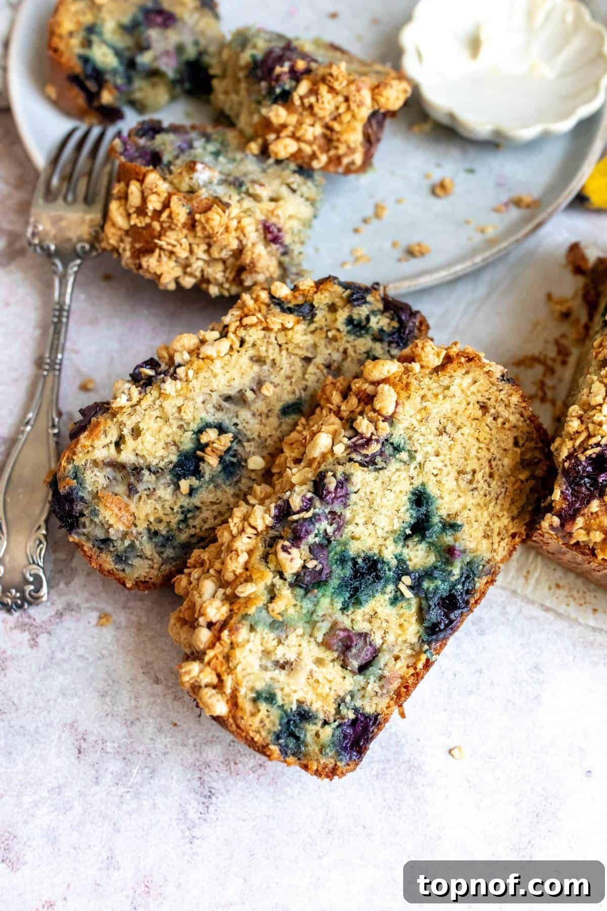 Ultimate Blueberry Banana Nut Bread 2 A freshly baked loaf of Blueberry Banana Nut Bread on a wooden counter with a fork, ready to be sliced and enjoyed.