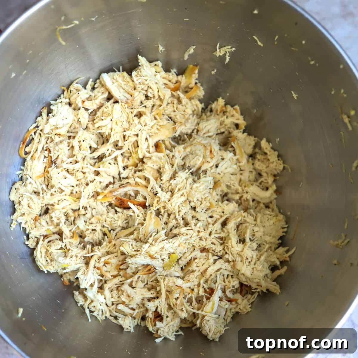 Spiced Chicken Salad 5 Shredded chicken in a stainless steel mixing bowl.