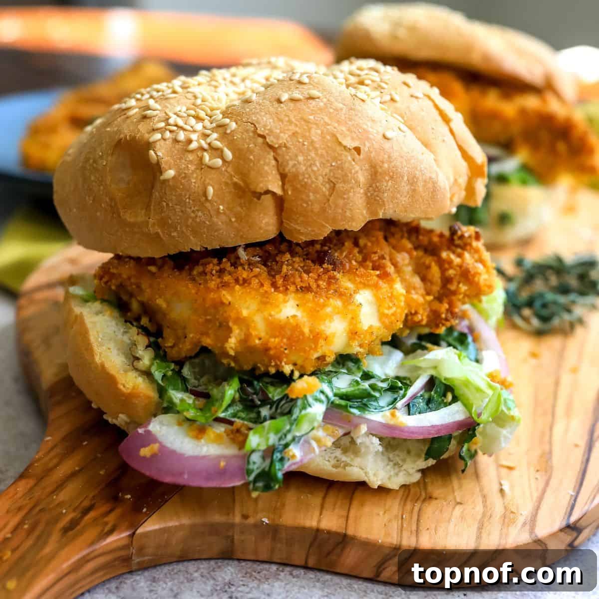 Golden Crispy Chicken Burger 2 Crispy chicken burger on a sesame bun with fresh lettuce, served on a rustic cutting board.