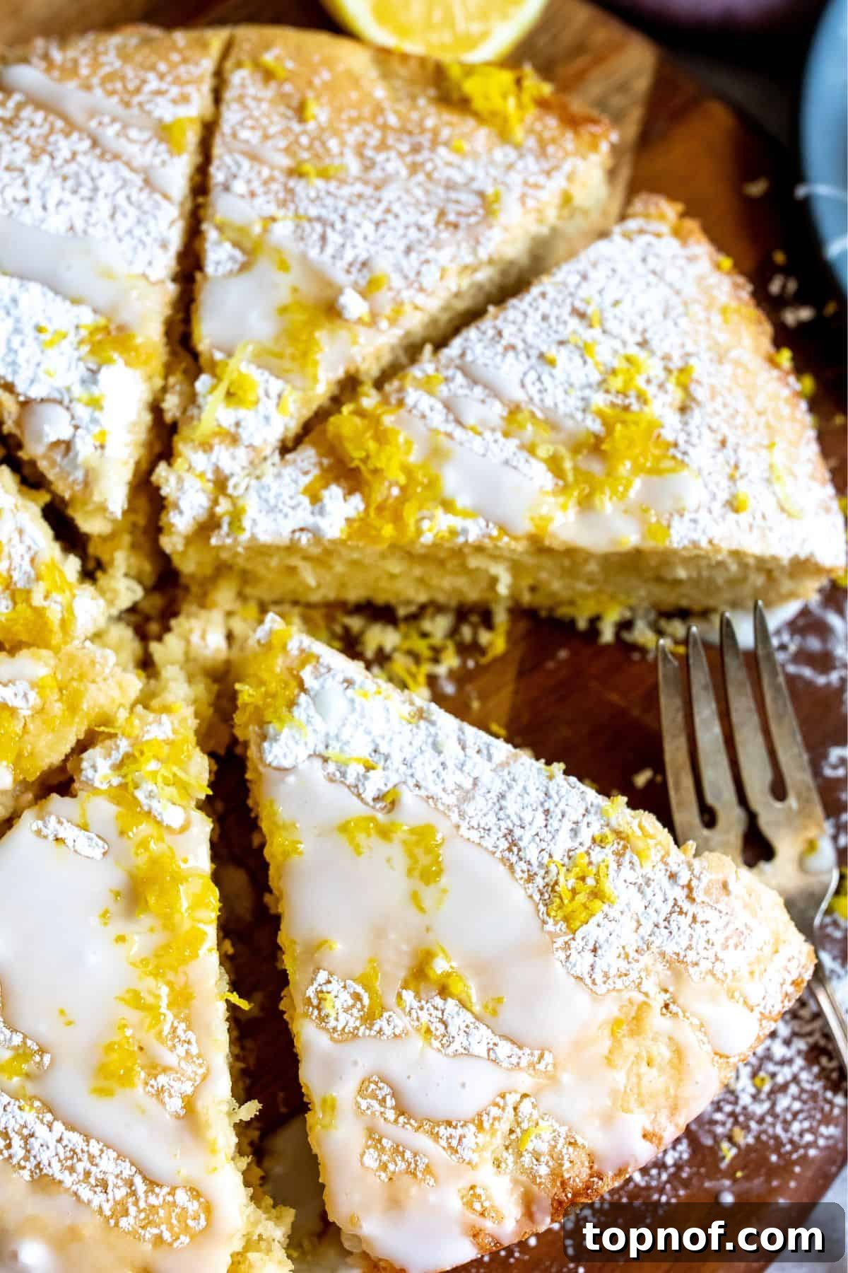 Amalfi Lemon Dream 2 A beautifully sliced Italian lemon cream cake on a rustic cutting board, with a fork ready to enjoy a piece.