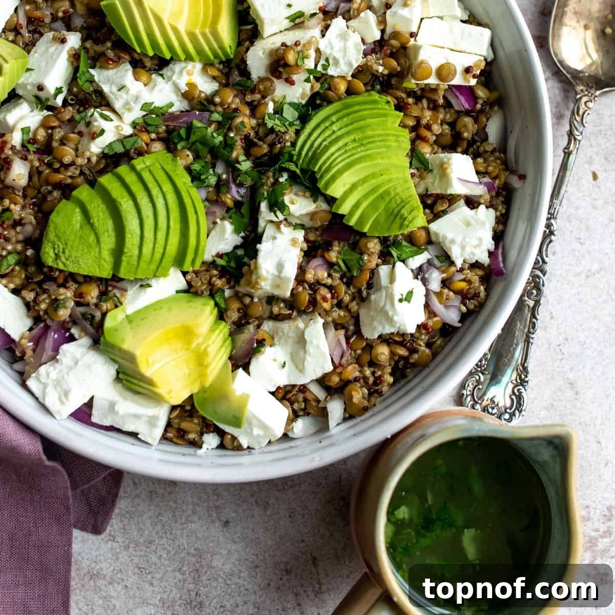 Vibrant Quinoa Lentil Power Bowl 5 Close-up of the prepared quinoa lentil salad with a bowl of lemon herb vinaigrette on the side, ready to be poured.