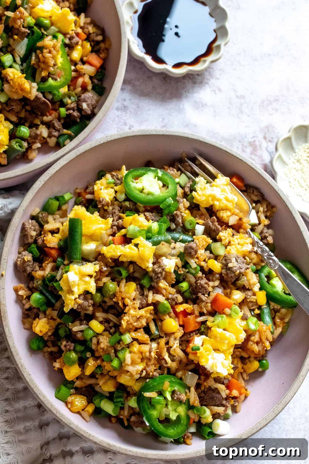 Sizzling Beef Fried Rice 6 Pink bowl with ground beef fried rice in it, soy sauce to the side.