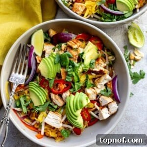 Two grey bowls with thai mango salad and a fork in the bowl on the table.