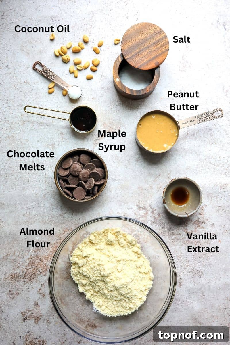 Wholesome Peanut Butter Chocolate Bars 3 Various ingredients for the buckeye bars, including almond flour, peanut butter, and maple syrup, displayed in large mixing bowls on a wooden surface.