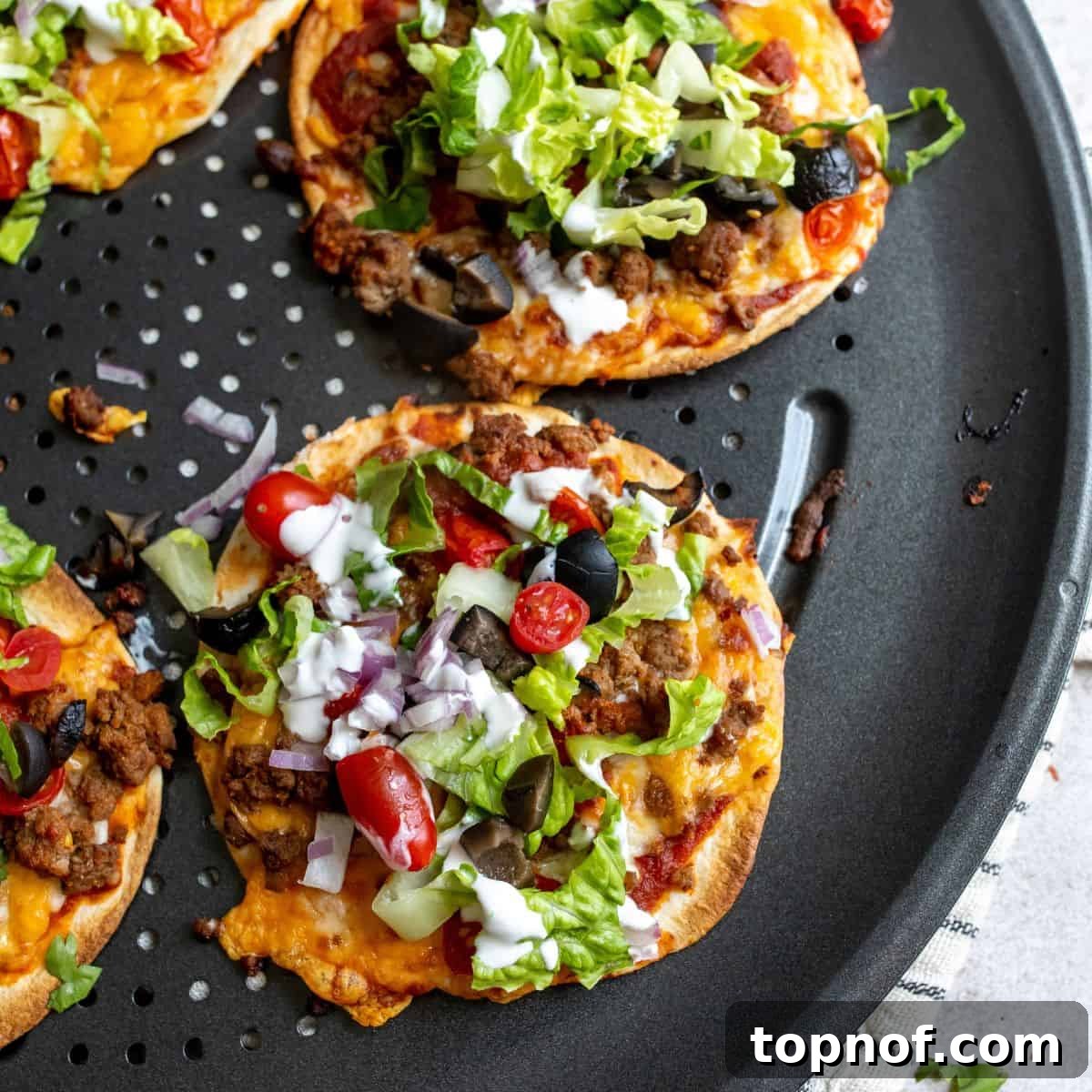 Tex-Mex Pizza 6 Several mini taco pizzas on tortillas, covered with melted cheese and fresh toppings, arranged on a baking sheet.