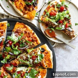 Delicious Taco Pizza ready to serve on a pan with a slice on a plate.