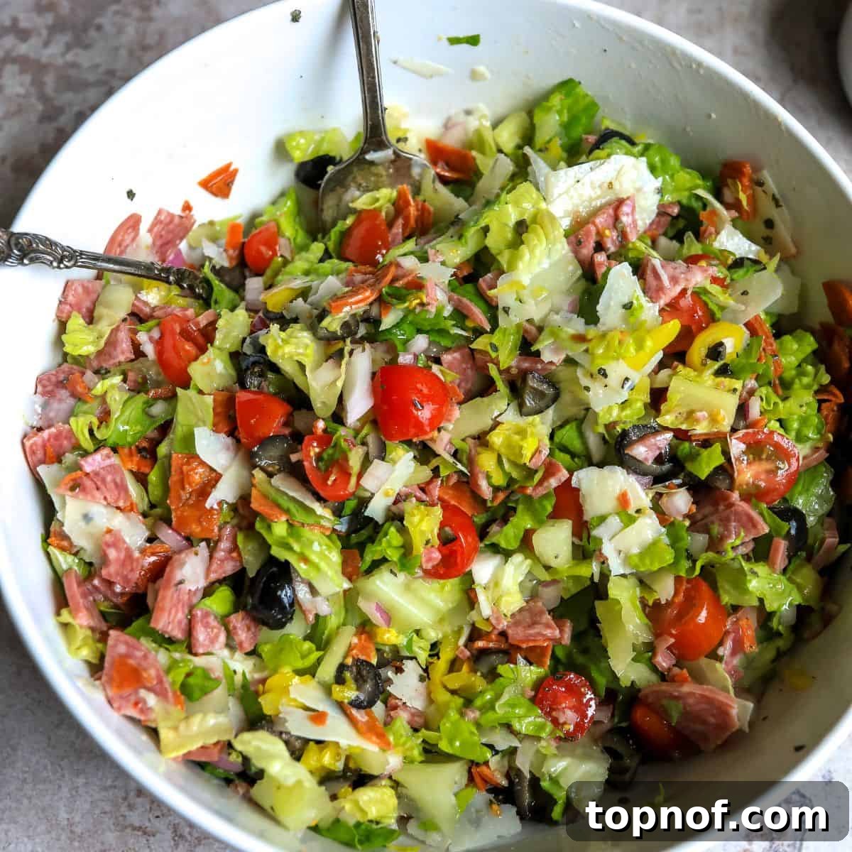 Tuscan Pinwheels 5 A vibrant and fresh chopped Italian salad with various ingredients mixed together in a white bowl, ready to be wrapped.
