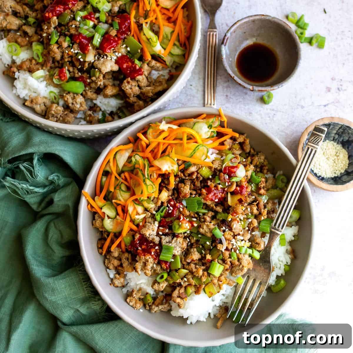 Sweet & Spicy Korean Ground Turkey 2 Two bowls with Korean ground turkey and cucumber and carrot salad in them, ready to serve.