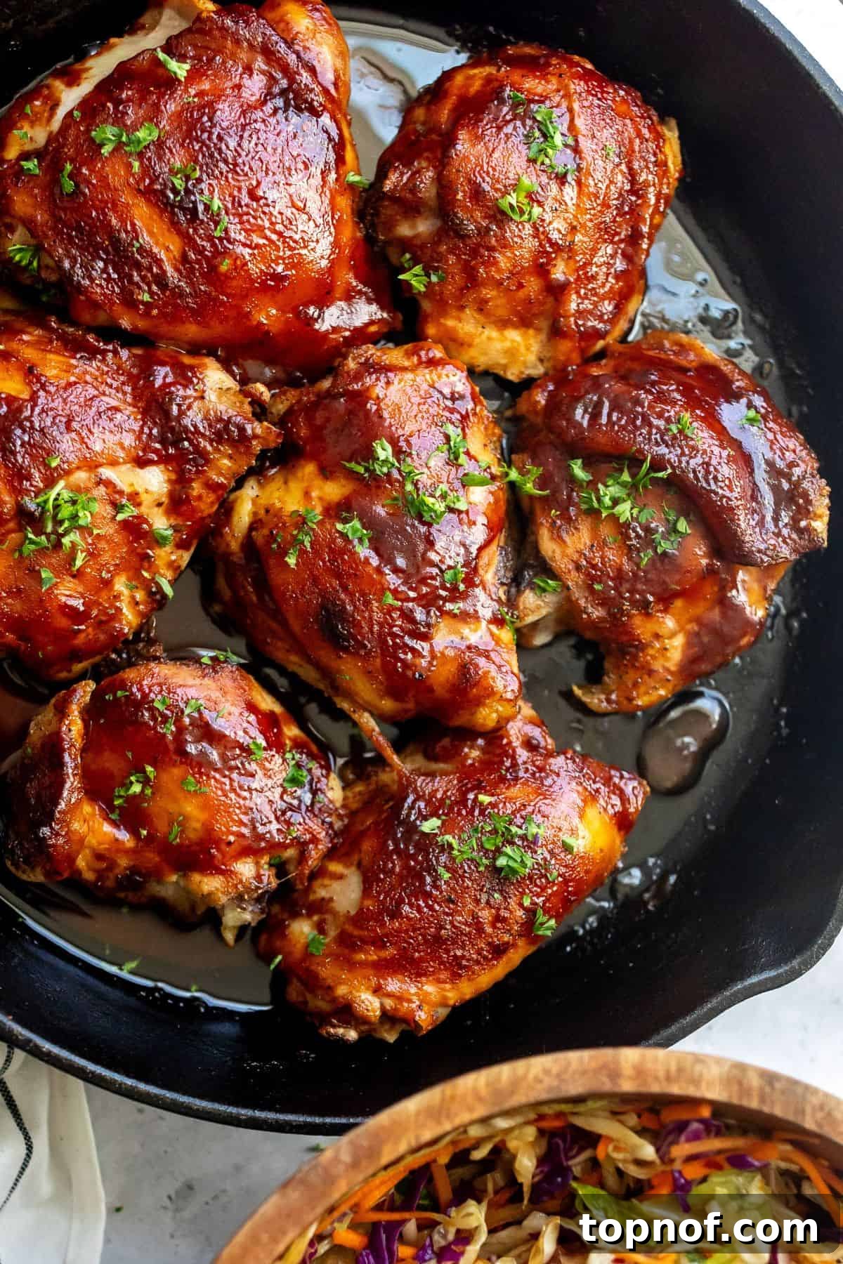 Glazed BBQ Chicken Thighs 2 Perfectly baked BBQ chicken thighs in a cast iron skillet, glistening with homemade sauce.