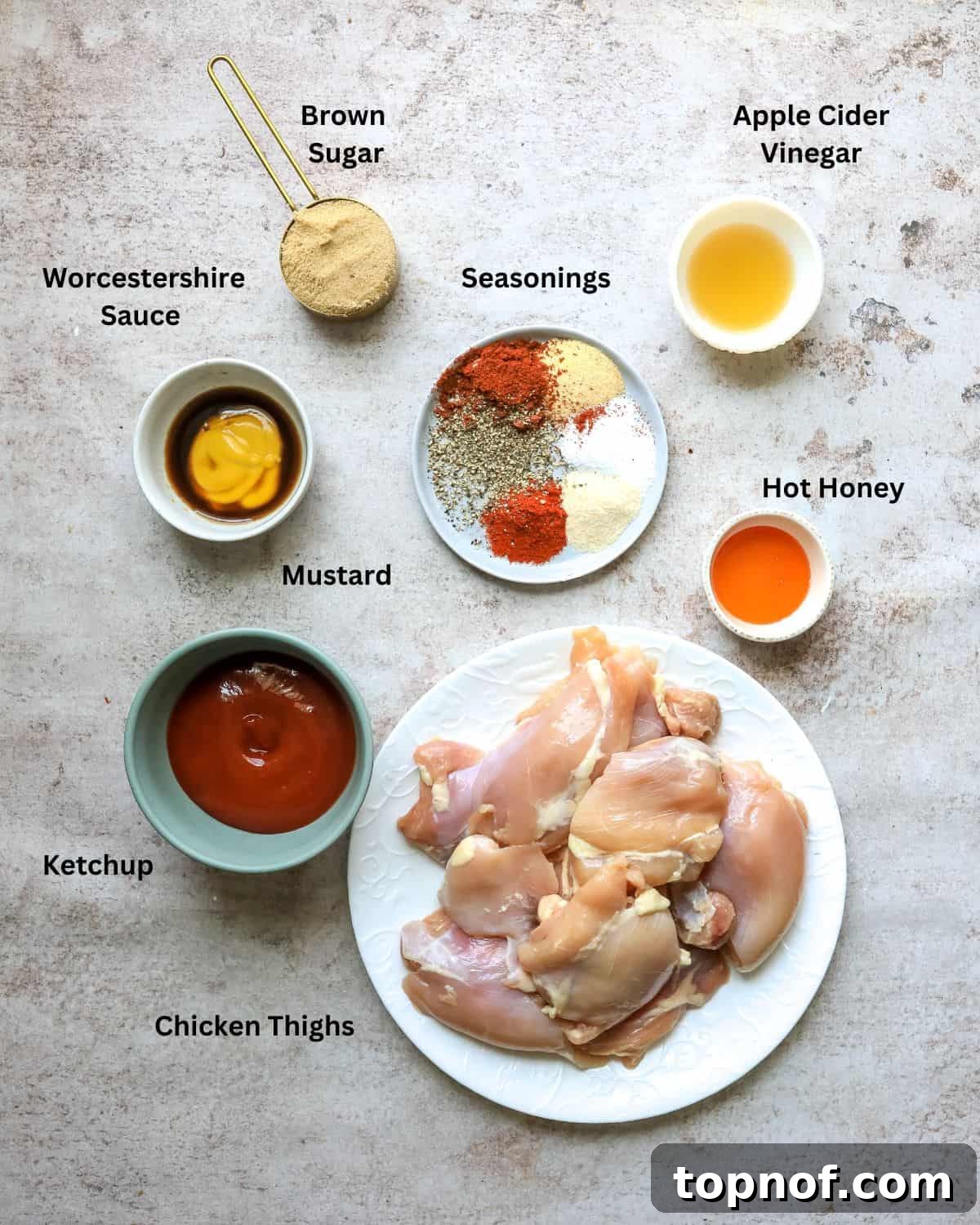Glazed BBQ Chicken Thighs 3 Assorted ingredients for oven BBQ chicken thigh recipe neatly arranged in small bowls and measuring cups on a kitchen counter.