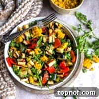 White bowl full of fresh grilled vegetables and a silver fork on a kitchen counter, depicting the final dish.