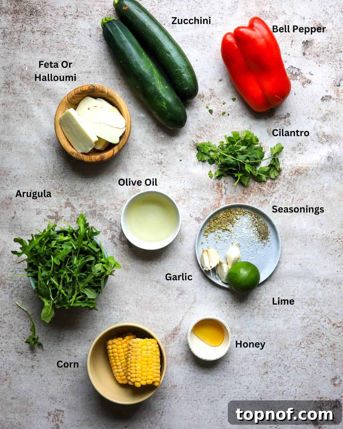 Smoky Zucchini Garden Salad 3 Ingredients needed to make grilled zucchini salad laid out on a kitchen counter, showing fresh zucchini, bell peppers, corn, halloumi, and dressing components.