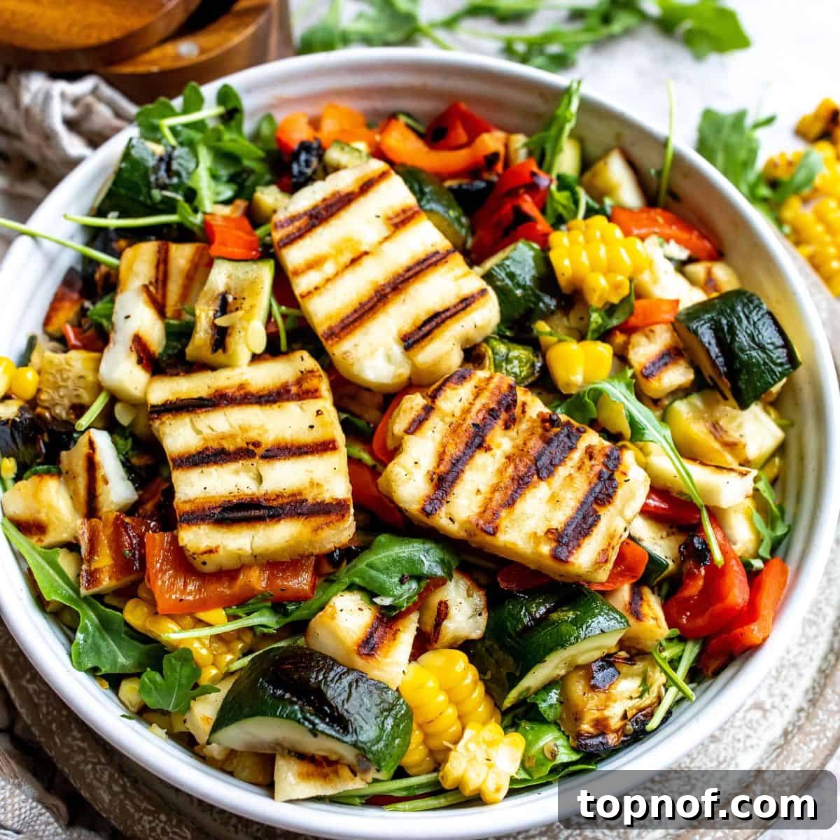 Smoky Zucchini Garden Salad 6 Beautifully arranged zucchini salad with grilled halloumi in a white bowl, garnished with fresh herbs, on a light-colored kitchen counter.
