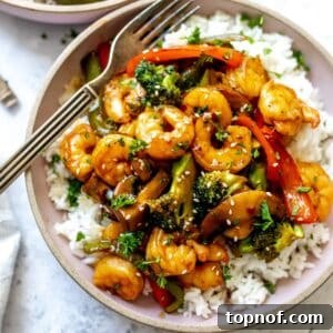 Teriyaki Shrimp Stir Fry with rice in a pink ceramic bowl, with a fork.