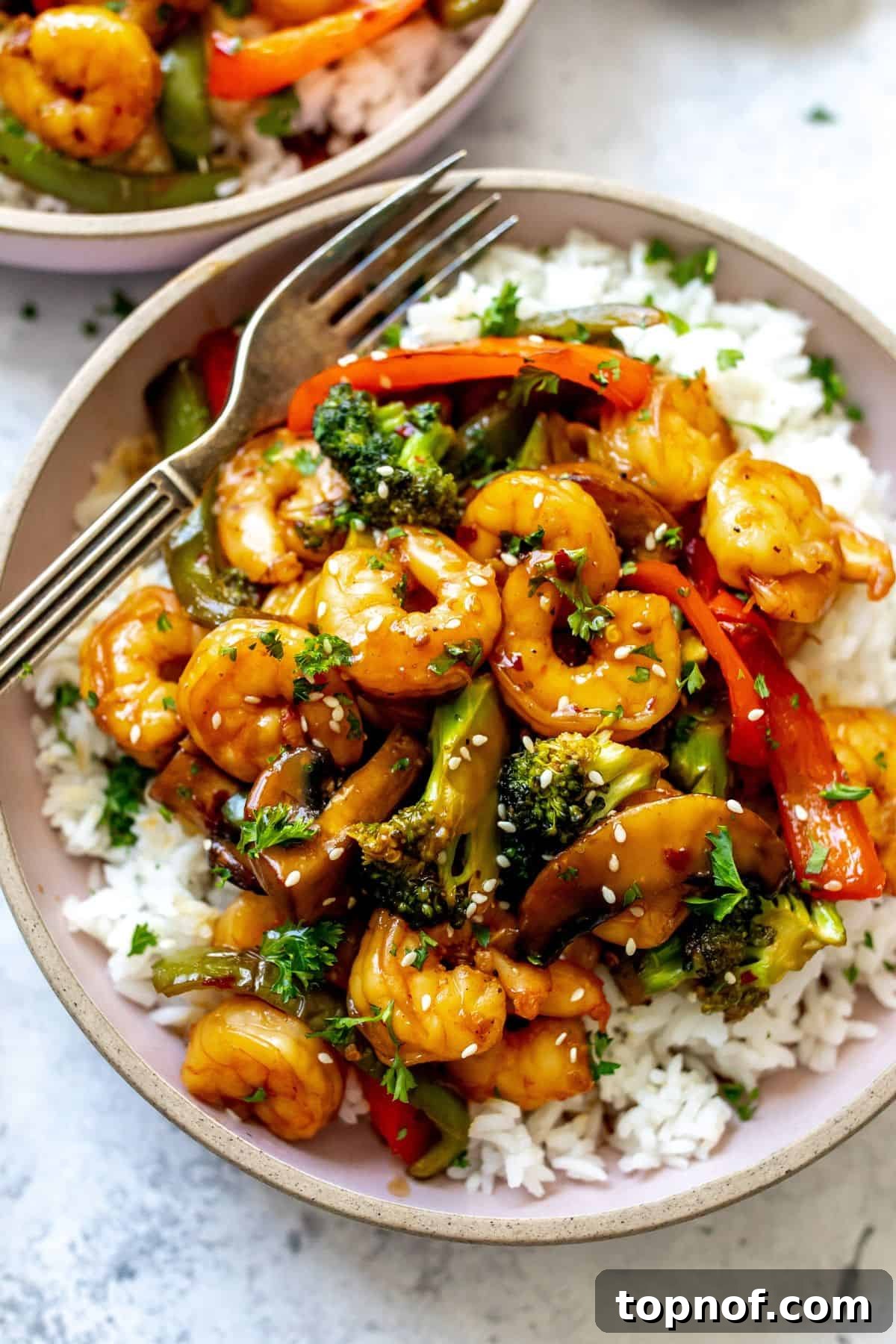 Teriyaki Glazed Shrimp Skillet 6 A single serving of Teriyaki Shrimp Stir Fry with white rice in a pink ceramic bowl, ready to eat, with a fork.