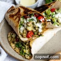 Savory Pesto Chicken Wraps, featuring vibrant pesto-coated chicken neatly tucked into a tortilla, presented on a ceramic plate.