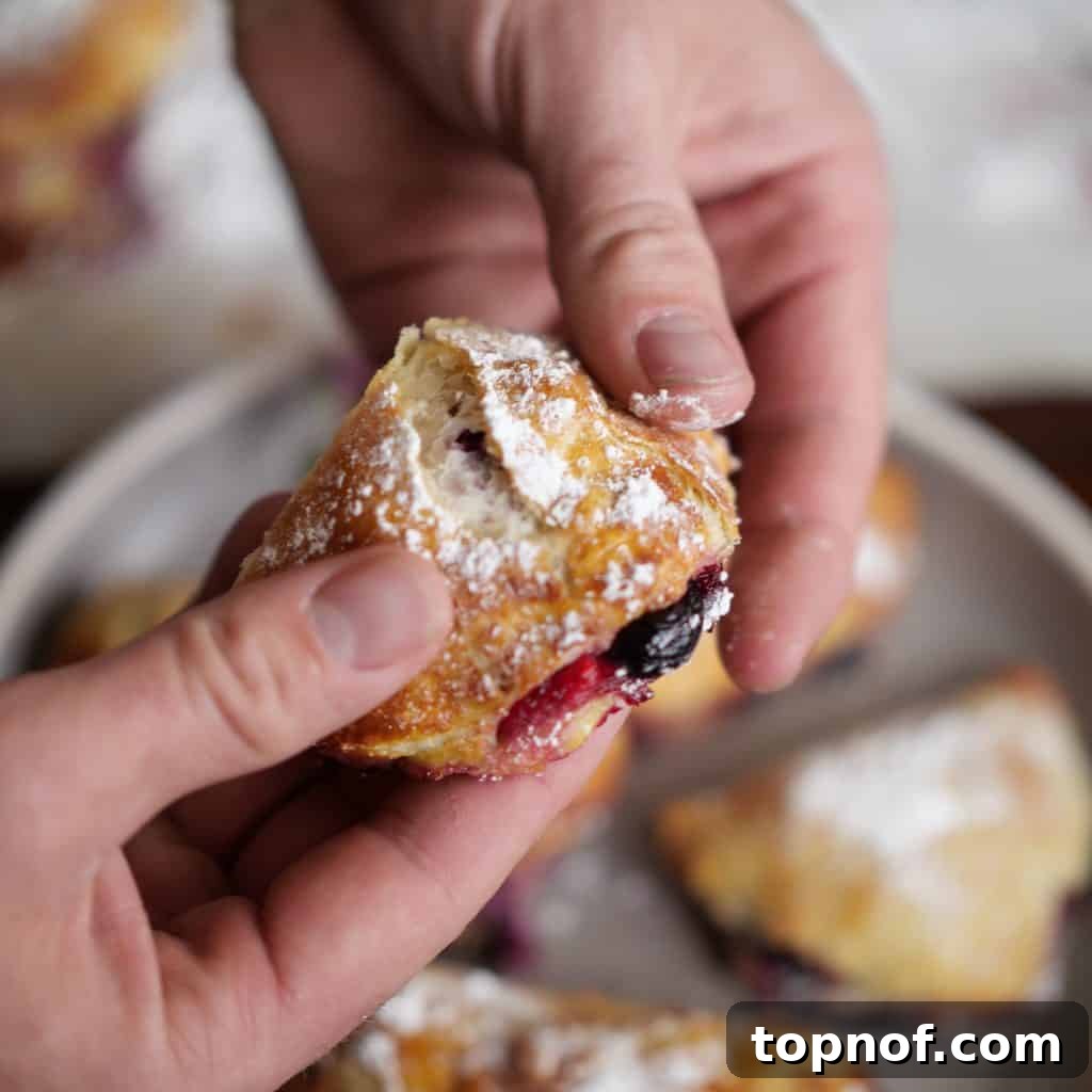 Effortless Blueberry Puffs 3 Breaking into an Easy Blueberry Turnover, revealing the creamy berry filling inside.