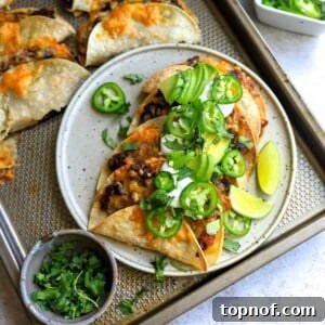 Crispy Black Bean Tacos on a white plate with limes and cilantro, sour cream and jalapeño.