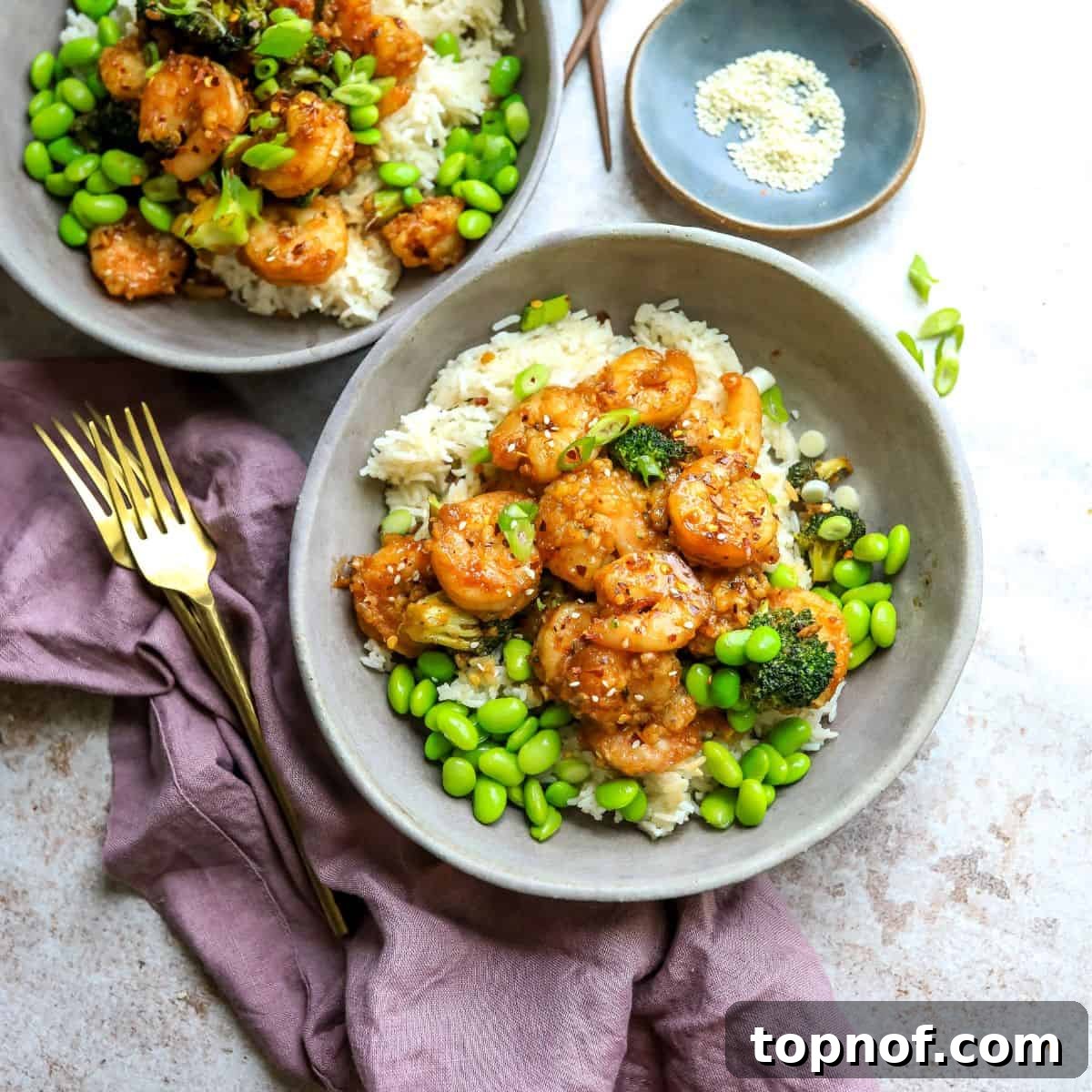 Grey ceramic bowls with rice and Mongolian shrimp with gold forks. 