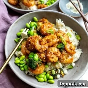 Mongolian shrimp in a grey bowl with edamame and a gold fork.