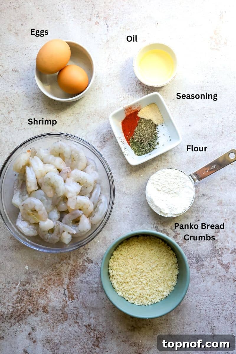 Golden Crunchy Panko Shrimp 3 All ingredients needed to make this crispy panko shrimp dish laid out on a kitchen counter with small bowls and measuring cups.