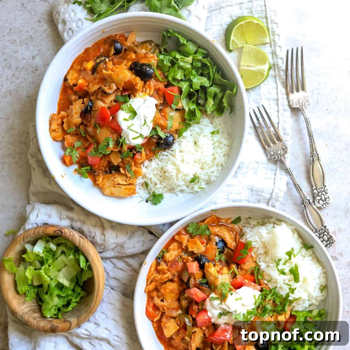 Melt-In-Your-Mouth Slow Cooker Chicken Enchiladas 2 White ceramic bowls with slow cooker chicken enchiladas and lettuce, a silver fork on the side.