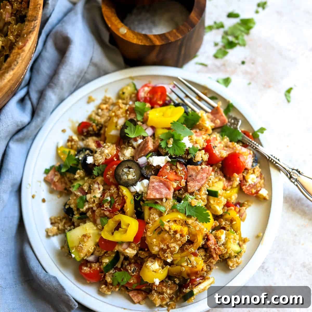 Tuscan Quinoa Medley 2 White plate with Italian quinoa salad, fresh veggies, and a silver fork on the side, showcasing the vibrant colors of the salad.